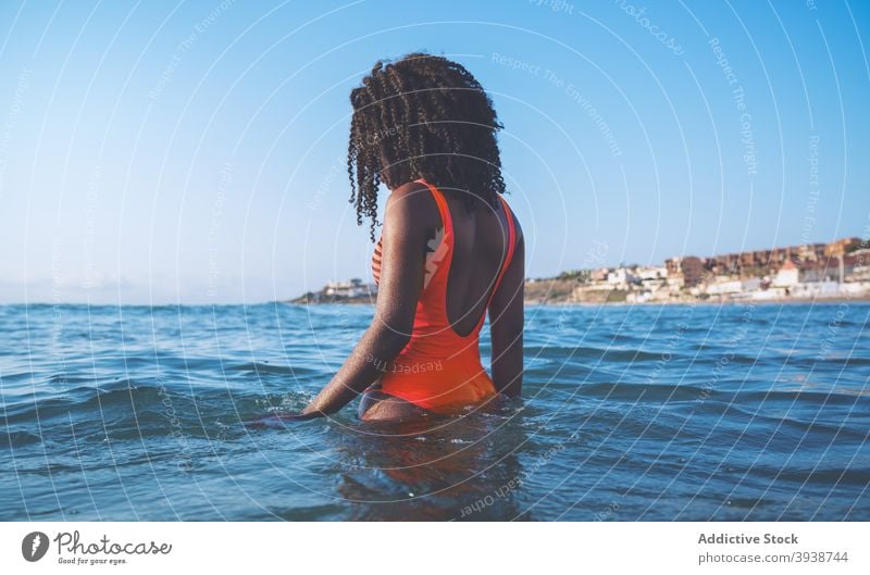 Anonyme schwarze fitte Frau entspannt sich im kräuselnden Meer an einem sonnigen Tag sich[Akk] entspannen MEER schwimmen Urlaub Stil Tourist Erholung Sommer
