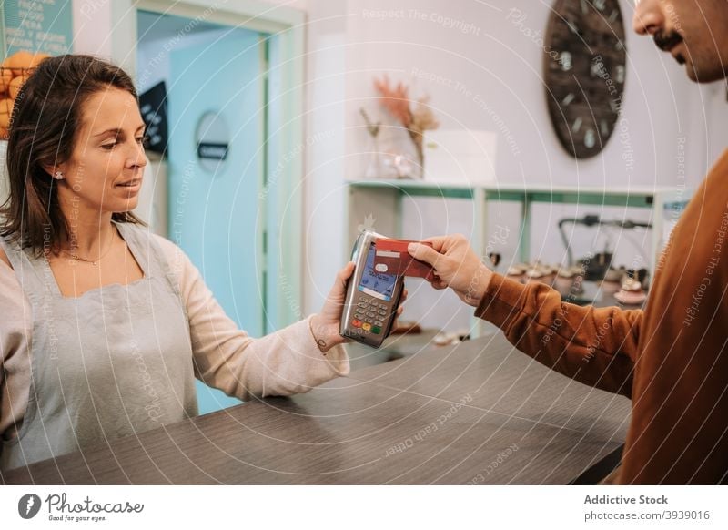 Kunde zahlt mit kontaktloser Karte im Café Zahlung nfc Kreditkarte Terminal Verkäufer Klient berührungslos Abfertigungsschalter bezahlen Kauf Transaktion