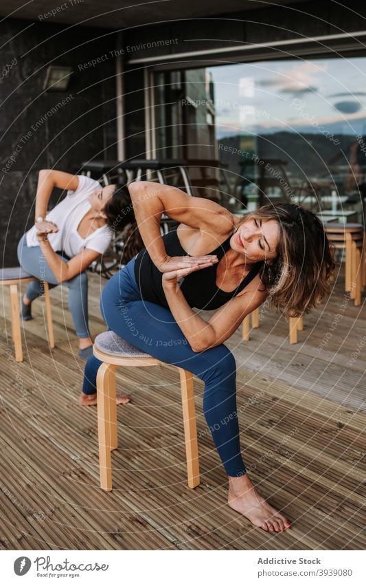 Frauen machen Yoga in gedrehter Krieger-Pose auf der Terrasse virabhadrasana Achtsamkeit Zusammensein Asana schlank ruhig Sportkleidung Harmonie friedlich