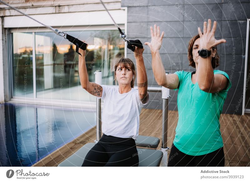Frau macht Yoga in Bootspose auf Pilates-Maschine Gleichgewicht Personal Ausbilderin Boot-Pose navasana abstützen Reformer Terrasse Gesundheit Wellness Übung
