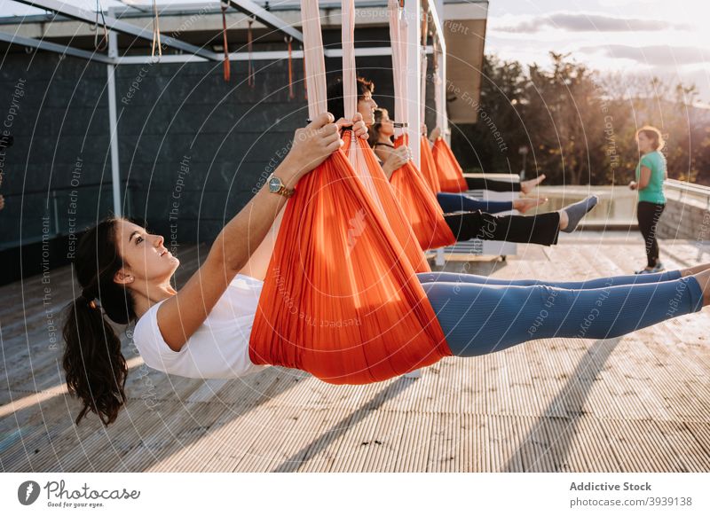 Frauen machen Yoga in Hängematten auf der Terrasse Klasse Menschengruppe üben hängen Asana Pose beweglich Sportkleidung sonnig Zusammensein Gesundheit