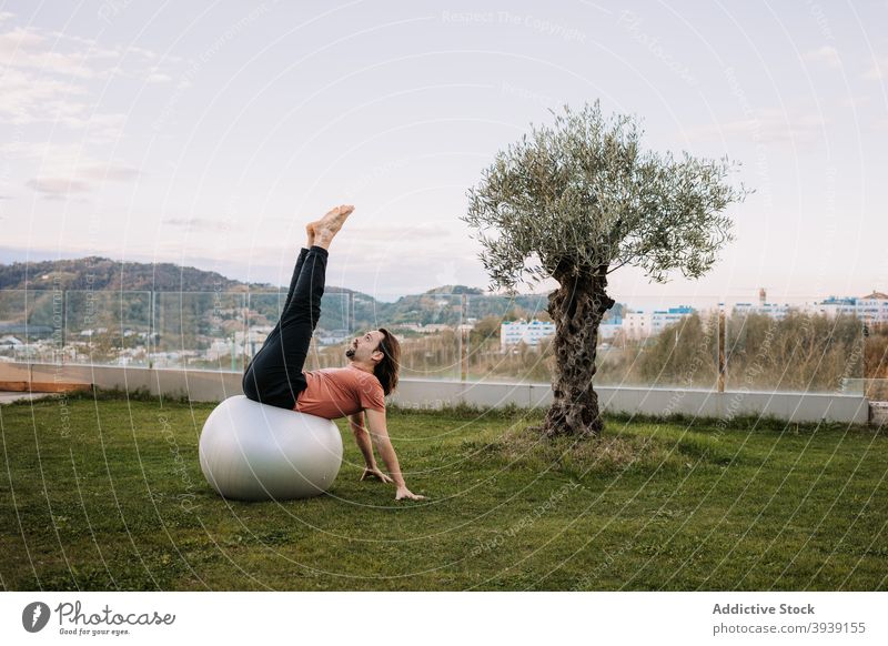 Mann macht Yoga in Wild Thing Posen auf fit Bälle Passform-Ball Pilates Wildes Ding Pose Gleichgewicht Asana Zusammensein beweglich camatkarasana Dehnung Rasen