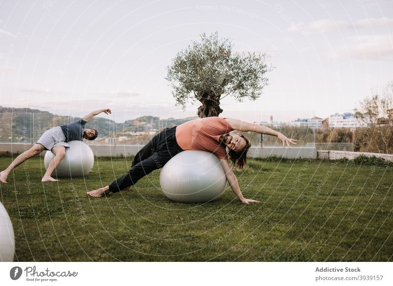 Männer tun Yoga in Wild Thing Posen auf fit Bälle Passform-Ball Pilates Wildes Ding Pose Gleichgewicht Asana Zusammensein beweglich camatkarasana Dehnung Rasen