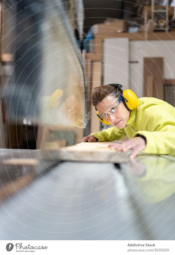 Seriöse Handwerkerin bei der Arbeit an der Tischsäge Frau Säge Holz Maschine Kunstgewerbler Hobelbank Fokus Tischlerarbeit Werkstatt Beruf hölzern Holzplatte