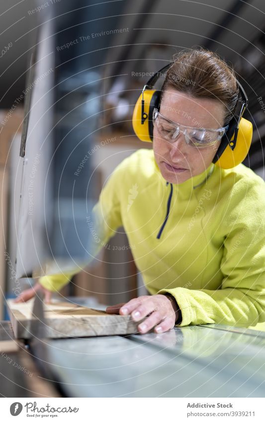 Seriöse Handwerkerin bei der Arbeit an der Tischsäge Frau Säge Holz Maschine Kunstgewerbler Hobelbank Fokus Tischlerarbeit Werkstatt Beruf hölzern Holzplatte