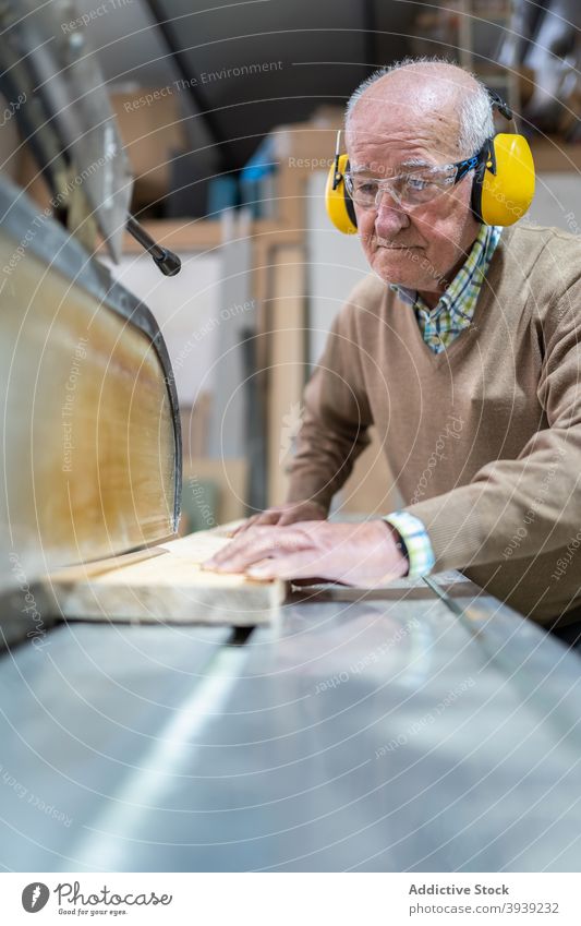 Seriöser Handwerker bei der Arbeit an der Sägetischmaschine Holz Maschine Kunstgewerbler Hobelbank Fokus Tischlerarbeit Werkstatt Beruf hölzern Holzplatte