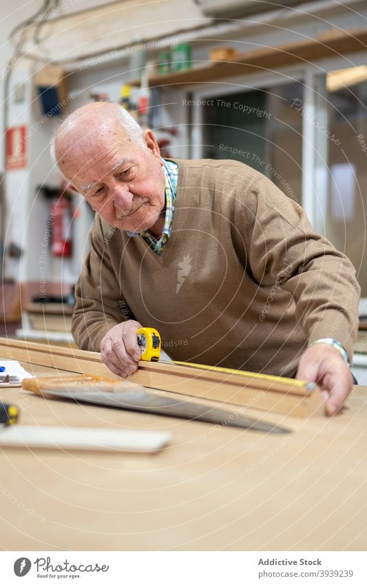 Senior-Handwerker bereitet Holz zum Sägen vor Mann messen Klebeband Tischlerin Werkstatt Maschine Arbeit Hobelbank Tischlerarbeit Kunsthandwerker Beruf männlich