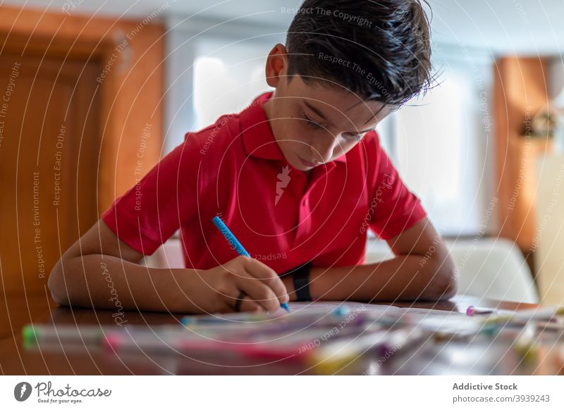 Schuljunge mit Marker bei den Hausaufgaben am Tisch Junge Anweisung schreiben lernen zeichnen Wissen Schönschreibheft Aufgabe Bildung primär Notebook farbenfroh