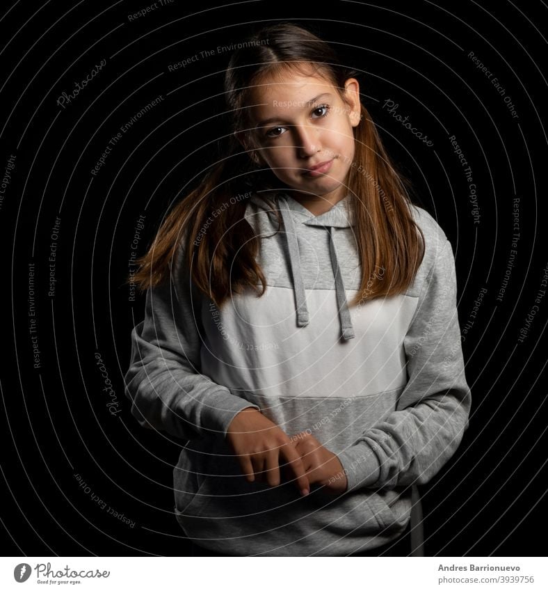Schönes kleines Mädchen in einem grauen Sweatshirt und mit zwei Zöpfen schauen mit lustigen Haltung auf einem schwarzen Hintergrund Tochter Freude positiv
