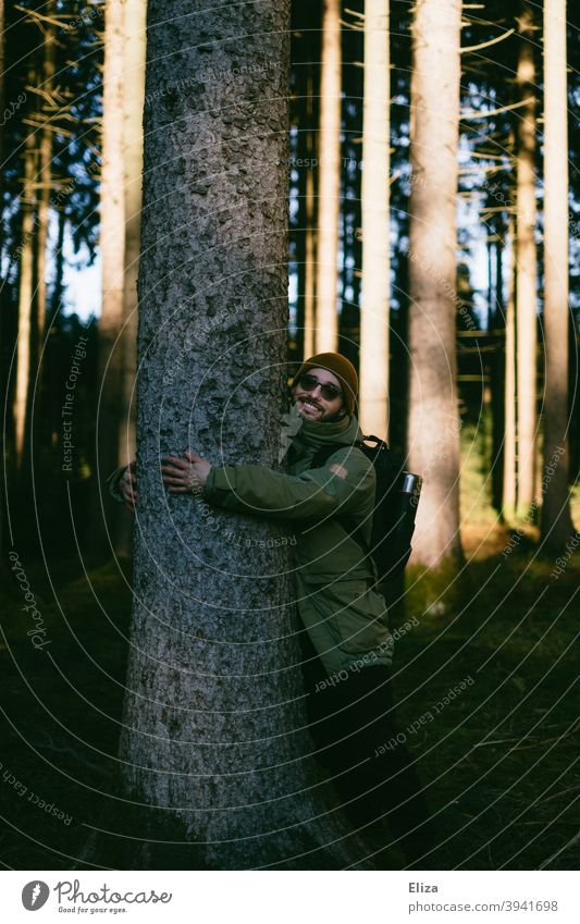 Ein Mann umarmt einen Baum im Wald ummarmen Umweltschutz Natur naturliebhaber naturverbunden Freude schützen Naturschutz Naturliebe Sonnenschein Winter Herbst