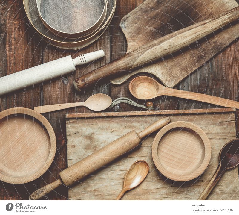 Vintage-Küchenartikel aus Holz: Sieb, Nudelholz, leere Löffel und runde Teller auf braunem Holztisch Speisekarte oben Hintergrund Holzplatte Essen zubereiten