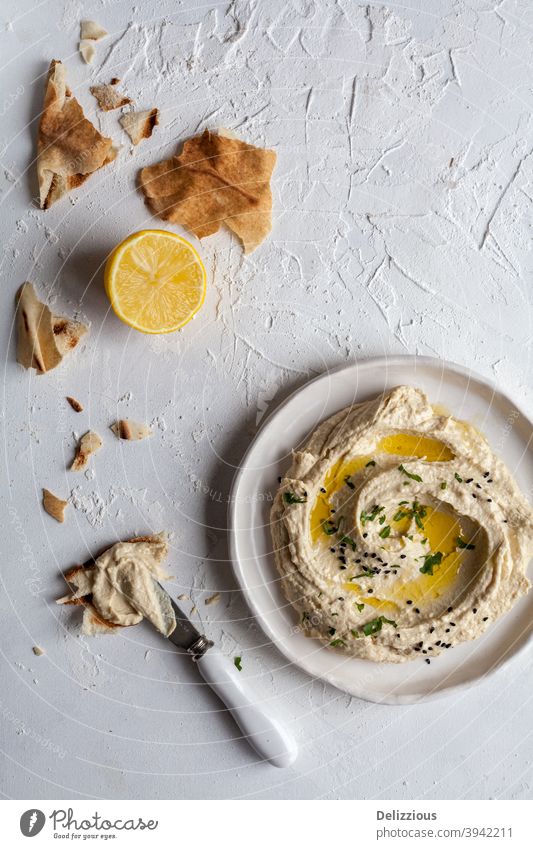 Draufsicht auf einen Teller mit Hummus mit libanesischem Fladenbrot und Zitrone auf weißem Hintergrund Amuse-Gueule arabisch arabische Küche Brot Kichererbsen