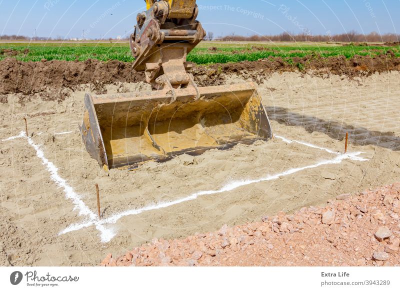 Bagger gräbt präzise innerhalb des markierten Bereichs auf der Baustelle genau Ausrichtung Arme Baggerlader Borte Begrenzung Eimer Kreide Tiefbau Bestimmen Sie