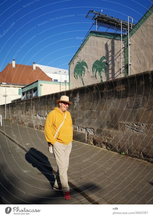 gelassen und entspannt Mann Straße Spaziergang flanieren alleine lächeln Freizeit Sonne sonnig gelb Hut Mauer Stadt Stadtspaziergang Schatten Sonnenbrille