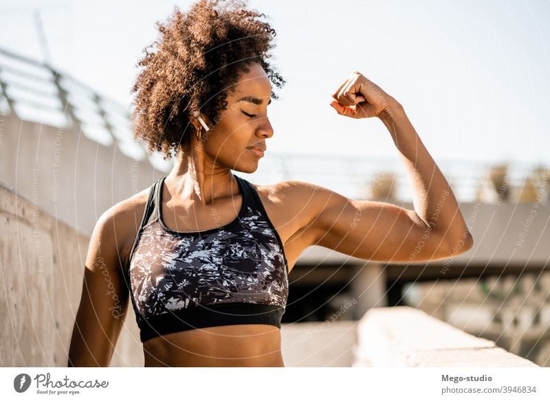 Afro-Athlet Frau flexing und zeigt Muskeln. Fitness Sport Übung aussruhen Pause im Freien sich[Akk] entspannen genießend Erholung Freizeit Ohrstöpsel sportlich