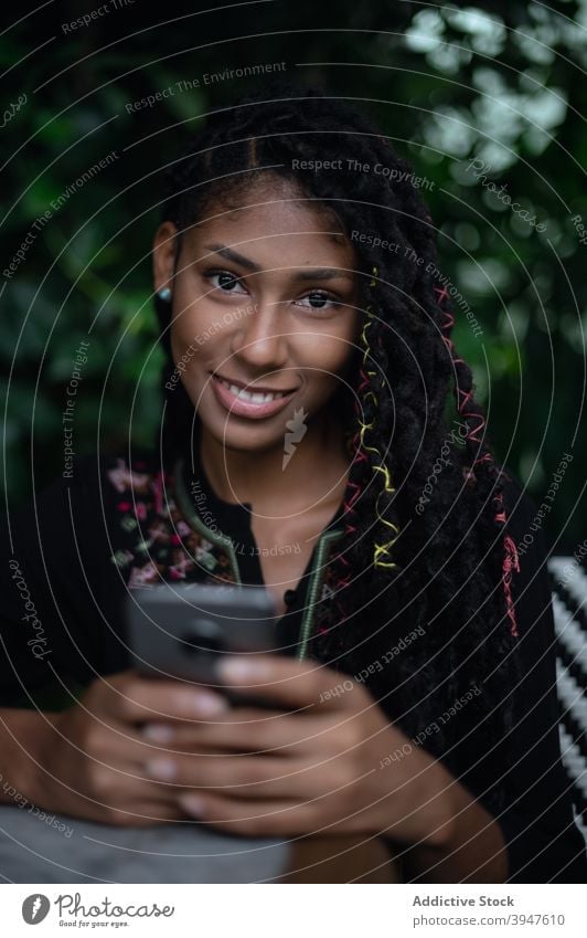 Afro latina Frau mit Smartphone im Restaurant 20s jung Kolumbien lateinamerikanisch Afro-Look schwarz attraktiv dreads Lifestyle eine Person benutzend