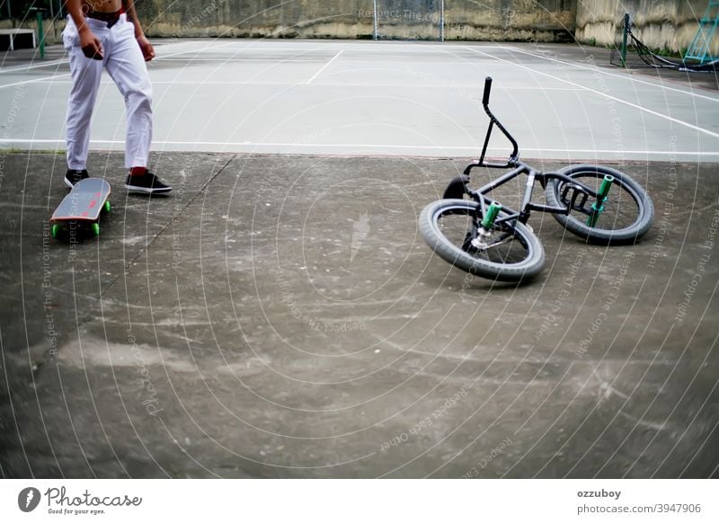 Hemdloser junger Erwachsener mit weißer Hose, der zwischen Skateboard und BMX-Rad auf einem Tennisplatz läuft ohne Hemd Skater laufen Spaziergang Sport