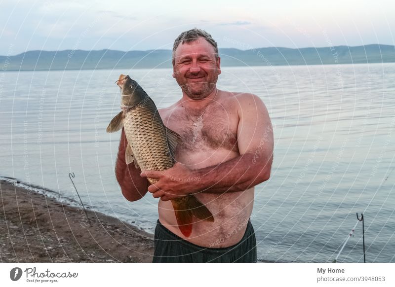 Stämmiger Mann mit großem Karpfen. Chakassien, Russland Herbst Hintergrund Strand schön blau Lager fangen Fisch Fischer Fischen gold Glück Hobby glücklich Natur