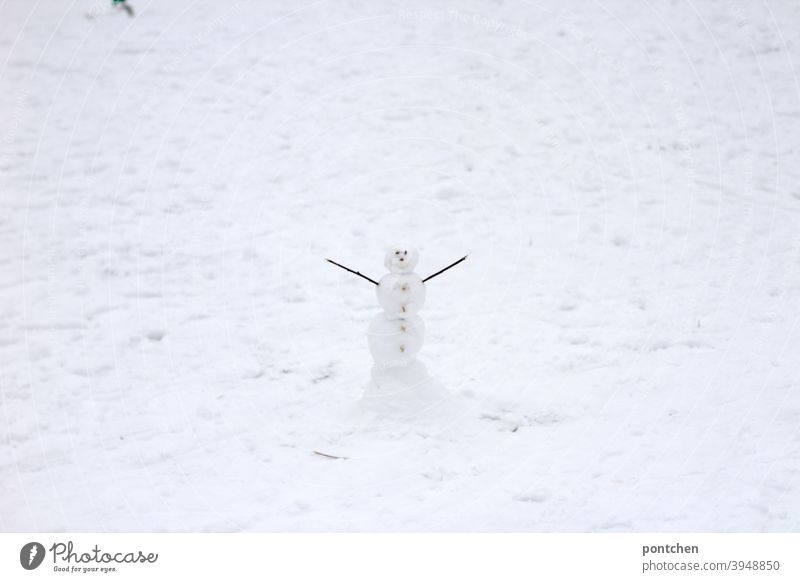 Ein kleiner Schneemann steht mit ausgestrecktem armen im Schnee. Winter schnee kinderspiel freude winter weiß kalt Spielen Natur Frost Jahreszeiten Klein