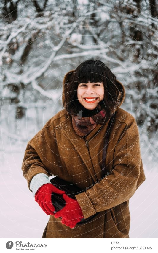 Schneeverliebt im Winter - Eine junge Frau steht im Schnee und lächelt vor Freude lachen winterlich brünett Lebensfreude Schneelandschaft verschneit spielen