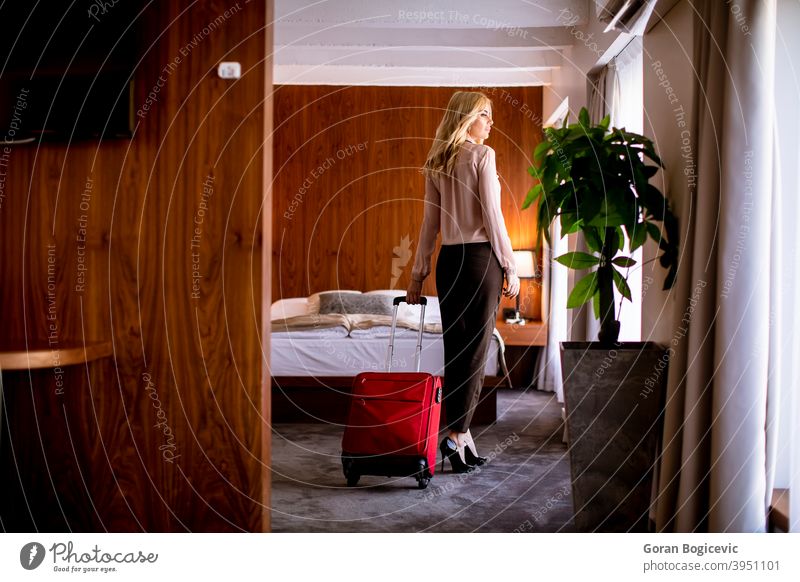 Junge Geschäftsfrau kommt in einem Hotelzimmer mit rotem Koffer an Erwachsener Ankunft Tasche Bett Schlafzimmer Business Kaukasier charmant Eleganz Frau