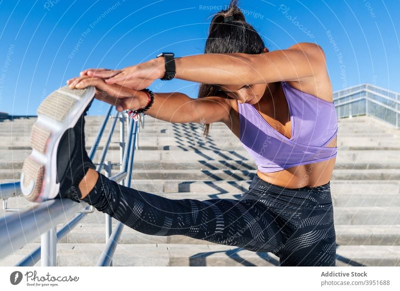 Schlanke Frau streckt die Beine beim Training Sportlerin Dehnung Athlet Großstadt Aufwärmen Vorwärtsbeuge beweglich Übung Sportbekleidung Reling Wegbiegung