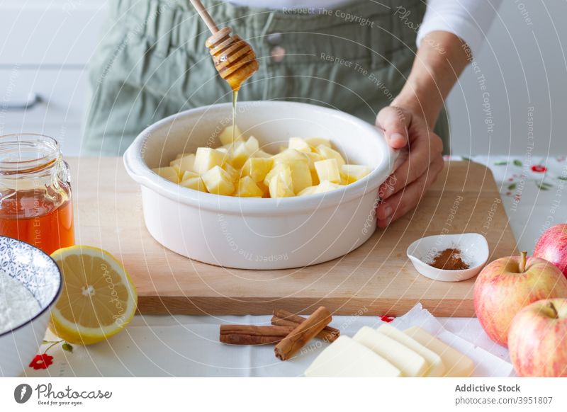 Ernteperson, die Äpfeln Honig hinzufügt Person Apfel Liebling hinzufügen Koch bröckeln Bestandteil Gebäck Küche heimwärts Tisch frisch Zitrone Mehl Zimt Butter