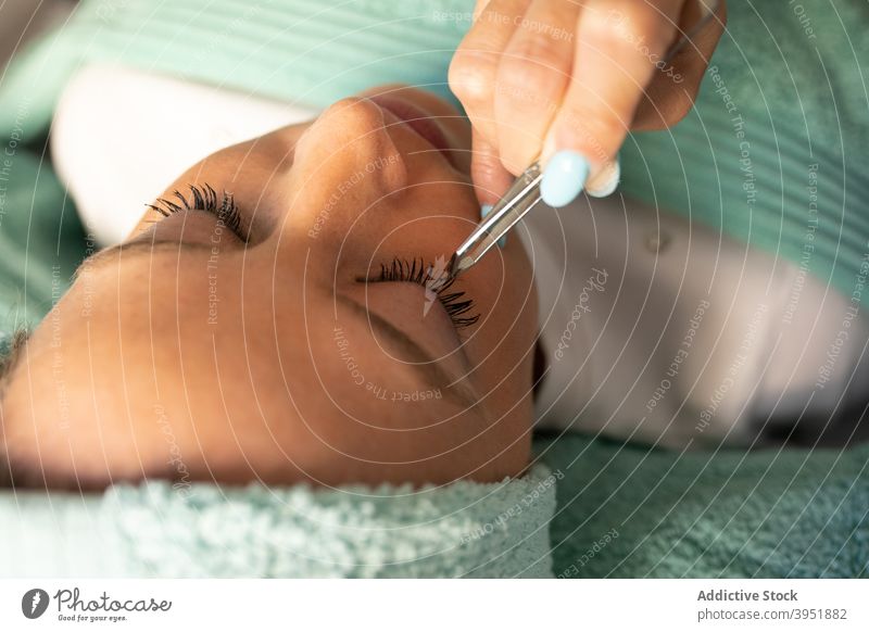 Kosmetikerin mit Pinzette vor Wimpernverlängerung Frauen kaschieren Verfahren Klient Augen geschlossen Lügen Prozess Werkzeug Job Leckerbissen vorbereiten