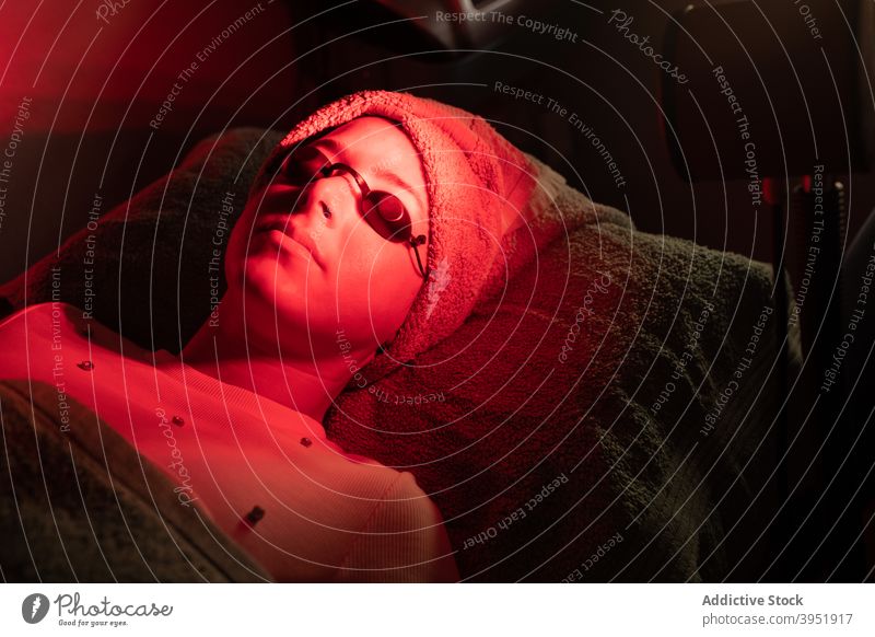 Junge Frau liegend unter rotem Licht während Hautpflege Behandlung Sitzung im Salon Frauen Lügen Verfahren Leuchtdiode Gesichtsbehandlung Leckerbissen Therapie