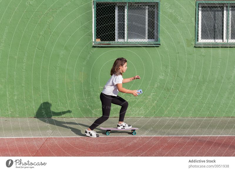 Stylish Mädchen mit Smartphone während Skateboarding auf Sportplatz benutzend Mitfahrgelegenheit Kreuzfahrtschiff-Brett Sportpark Süchtige Aktivität Hobby