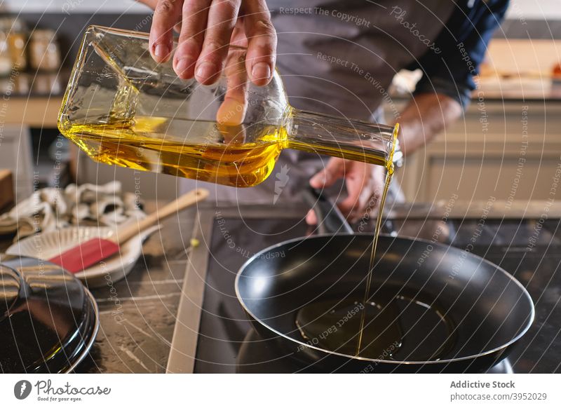 Unerkennbarer Mann gießt Öl in einen Kochtopf Erdöl eingießen Küche heimwärts hinzufügen Küchenchef modern Flasche männlich Bestandteil Rezept Lebensmitte reif