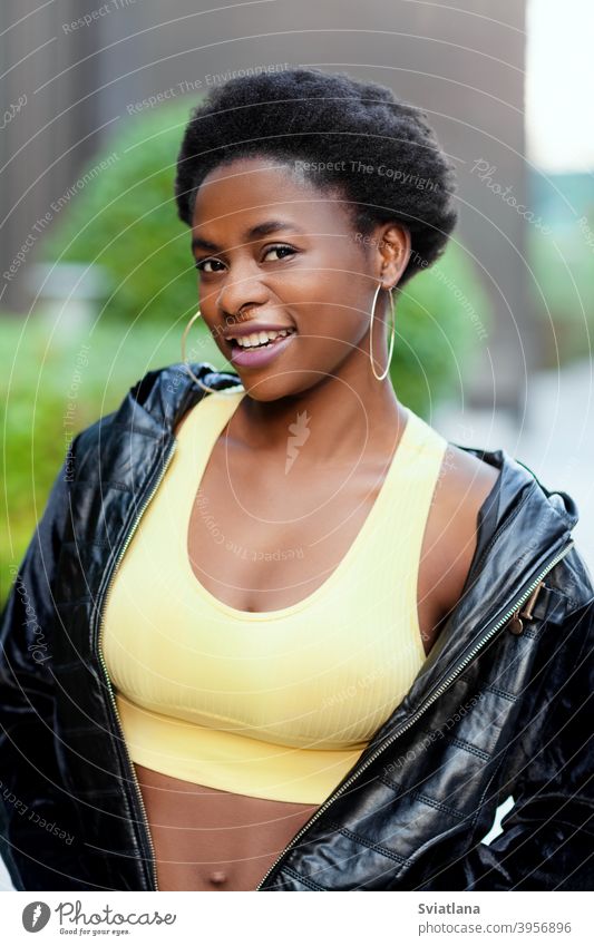 Junge afroamerikanische Frau, die eine Jacke trägt, lächelt und schaut in die Kamera Mädchen schwarz Porträt Afrikanisch Glück jung Amerikaner posierend Blick