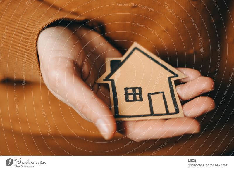 Eine Person hält ein gemaltes Haus in der Hand Zuhause Hauskauf Immobilie Eigenheim kaufen neues Zuhause Hypothek halten Geborgenheit wohnen Kapitalanlage