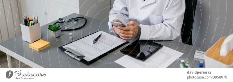 Ärztin benutzt Handy während der Arbeit Arzt Frau arbeiten benutzend Mobile Arztpraxis Texten plaudernd medizinisch Büro Transparente Netz Kopfball Panorama