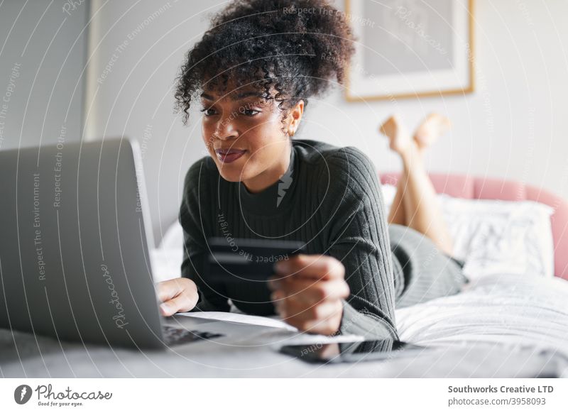 Junge Frau liegt auf dem Bett zu Hause mit Laptop-Computer mit Kreditkarte zum Einkaufen online Lügen Schlafzimmer Debitkarte Banking Auszahlungstag Technologie