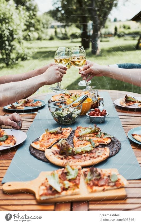 Freunde machen Toast während Sommer-Picknick im Freien Abendessen in einem Haus Garten Hinterhof Getränk Feier Speise trinken Essen Familie Festessen