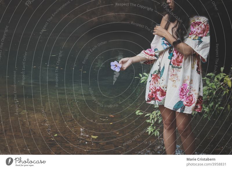 Eine Frau auf einem Teich, die eine Blume hält, zeigt das Konzept von Wellness in der Natur, Achtsamkeit und geistiges Wohlbefinden Weiblichkeit Eleganz