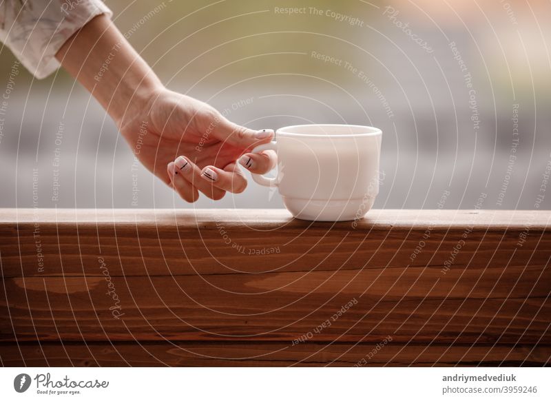 Morgen Kaffee Tasse. Weibliche Hand hält weiße Tasse Morgen heißes Getränk - Kaffee oder Tee auf dem Balkon auf dem Hintergrund der Bergnatur. trinken Frau