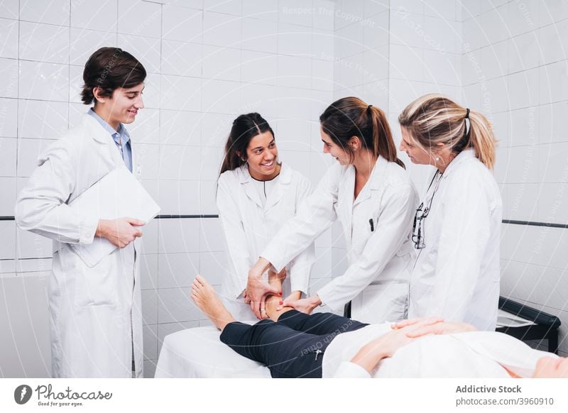 lächelnde Gruppe von Ärzten untersucht das Bein eines Patienten in einem Krankenhaus crotochisch Analyse Analysieren Anatomie Knochen Klinik Mantel Diagnostik