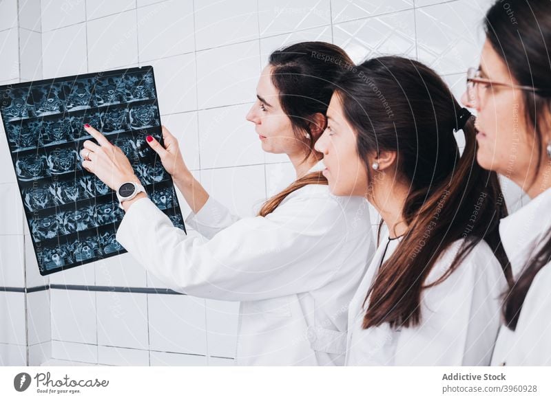 Arzt in Uniform zeigt zwei anderen Ärzten ein Röntgenbild crotochisch Analyse Analysieren Anatomie Knochen Überprüfung Klinik Mantel Kollegen Berater Diagnostik