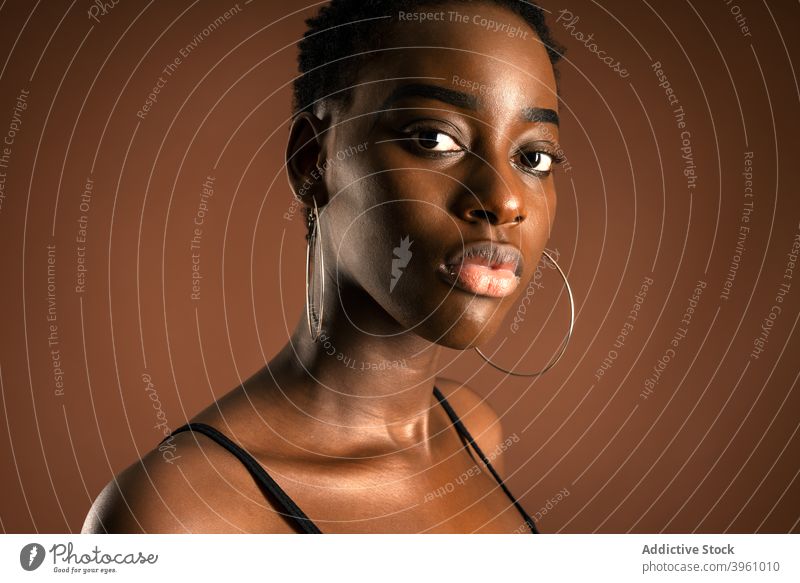Schlankes afroamerikanisches Modell stehend auf braunem Hintergrund Frau schlank Stil Anmut lässig Outfit Kurze Haare schlanke ethnisch schwarz Afroamerikaner
