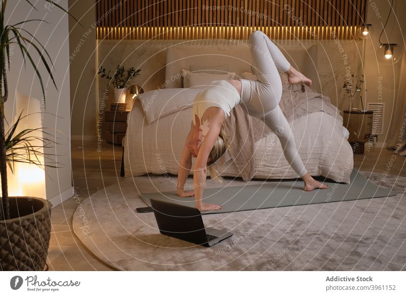 Frau stehend in Rad-Pose auf Yoga-Matte Radstellung beweglich üben Tutorial Asana Dehnung Laptop heimwärts online Lektion Achtsamkeit Zen Unterlage Apparatur