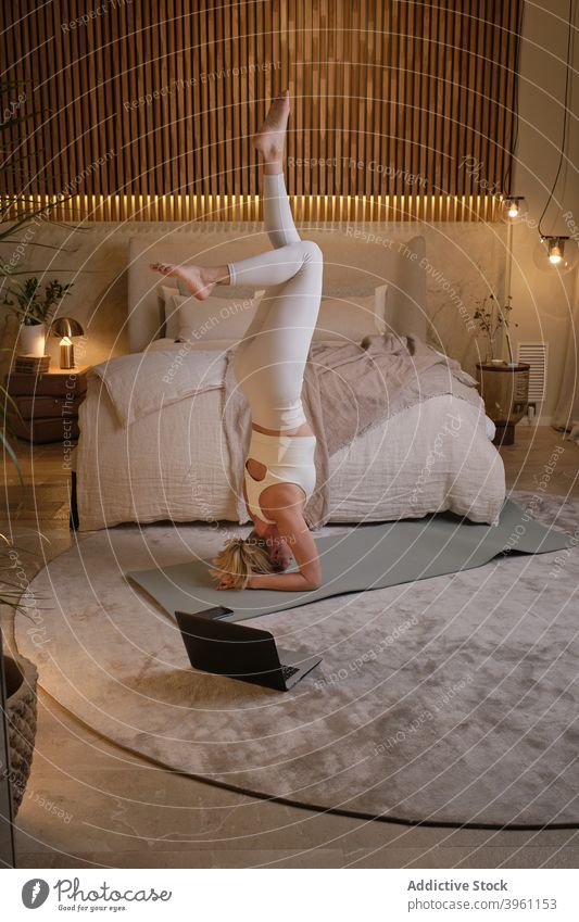 Schlanke Frau macht Yoga in Unterstützter Kopfstand Position üben Gleichgewicht Asana Tutorial Laptop online Zen heimwärts unterstützte Kopfstand-Pose Lektion