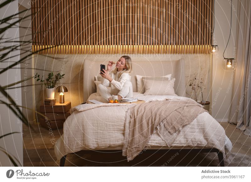 Frau nimmt Selfie beim Frühstück im Schlafzimmer Smartphone Morgen Lebensmittel heimwärts Selbstportrait Bett Gerät Apparatur jung Telefon fotografieren ruhen