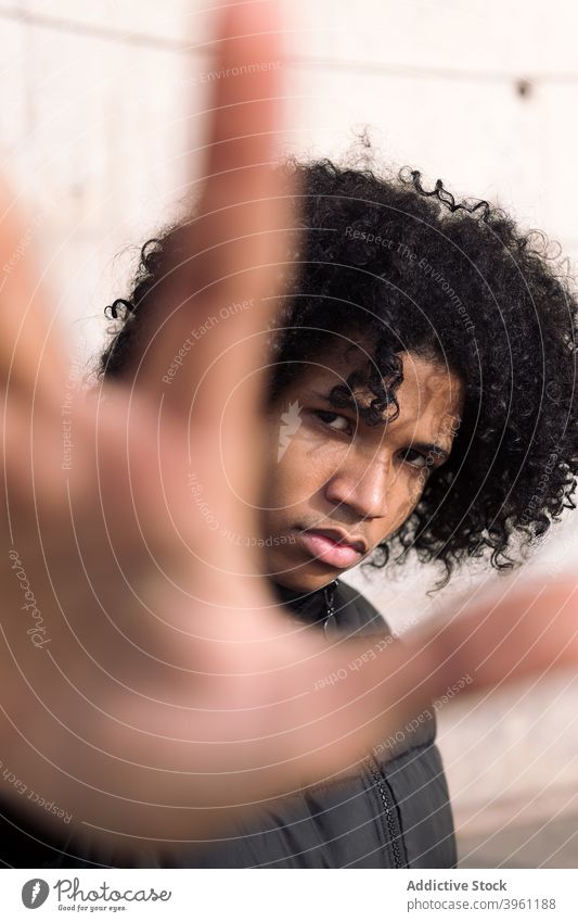 Schwarzer männlicher Jugendlicher mit protestierender Geste Mann nein ausdehnen Hand stoppen gestikulieren ernst Teenager jung selbstbewusst Einstellung Deckung