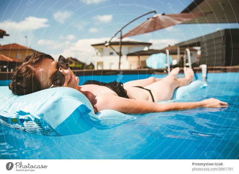 Junge Frau im Bikini auf Float-Matratze in rundem überirdischem Schwimmbecken. Lifestyle Wasser Sommer Sonne Pool aufblasbar offen Erholung erfrischend