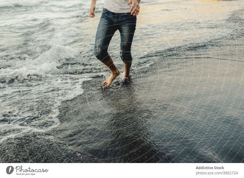 Mann geht entlang nassen sandigen Meeresufer MEER Strand winken Barfuß Reisender Sand Küste Ufer männlich Sonnenuntergang Urlaub Lifestyle Spaziergang reisen