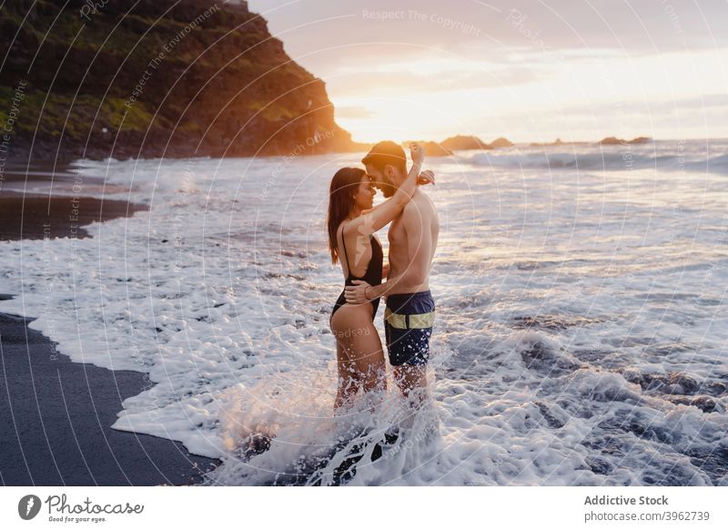 Glückliches Paar mit Spaß in schaumigen Meer Wellen MEER winken romantisch Liebe Spaß haben Strand Zusammensein Sonnenuntergang Wasser Zuneigung jung Teneriffa