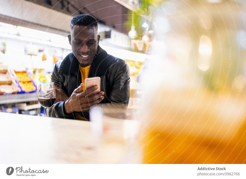 Schwarzer Mann beim Surfen auf dem Smartphone im Café Browsen heiter soziale Netzwerke Nachricht Wein Kälte Wochenende männlich schwarz Afroamerikaner ethnisch