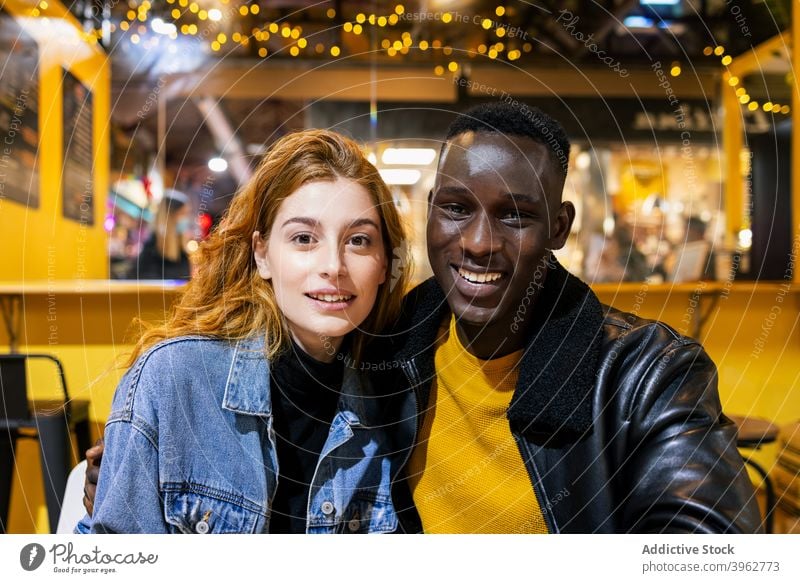 Multiethnisches Paar entspannt im Café Umarmen heiter Zusammensein jung Kälte Wochenende Lächeln Partnerschaft multiethnisch rassenübergreifend vielfältig